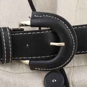 Detail of black leather belt with golden buckle and white stitching on a beige dress