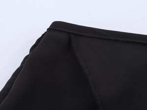 Gros plan des coutures précises et de la texture du tissu noir sur l'ensemble