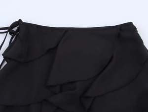 Détail macro de la jupe noire à volants avec ourlet superposé et lien à la taille