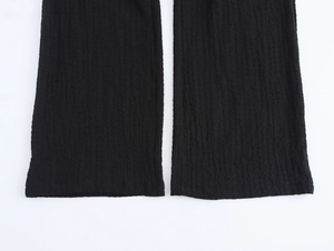 Detailed texture view of black wide leg pants with vertical crepe fabric and neat hemline