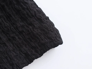 Macro shot of high-quality black pleated fabric with textured wavy grain and elastic detail