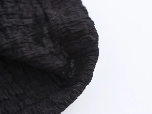 Close-up of smocked black fabric texture showing detailed crinkled material design