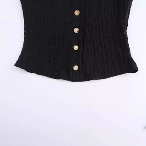 Detail of black seersucker vest with four vintage brown buttons on textured fabric