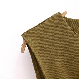 Olive green corduroy sleeveless dress with wide straps on a wooden hanger against white background