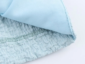 Detail of light blue sleeveless vest set showing smooth lining and wavy pleated fabric