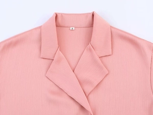Close-up of pink pleated fabric texture on double-breasted suit blazer lapel