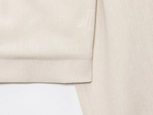 Close-up of beige cotton-linen fabric jacket with neat hem stitching and natural texture