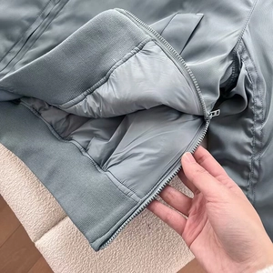 Macro view of grey-blue bomber jacket featuring metal zipper and ribbed hem detailing