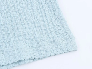 Macro shot of light blue seersucker fabric texture with detailed double-stitched hem