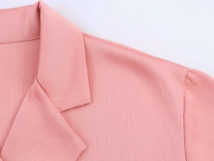 Close-up detail of pink double-breasted blazer showing vertical crinkle texture and stitching