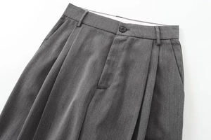 Vue détaillée du pantalon gris foncé avec bouton à la taille et plis classiques