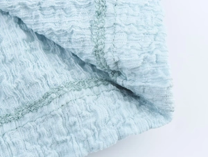 Macro detail of light blue pleated fabric showing neat interior seams and textured finish