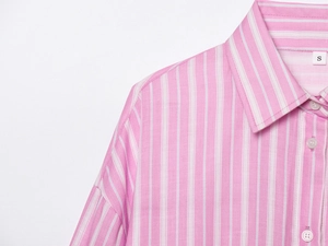 Detail eines rosa gestreiften Hemdkragens mit weißen Knöpfen und Größe-S-Etikett