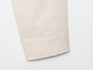 Macro detail of beige linen blend jacket cuff with neat single-needle stitching texture