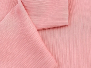 Detailed macro view of pink pleated chiffon fabric texture with soft vertical creases