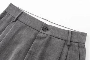 Vue détaillée du pantalon gris foncé avec fermeture à bouton et design à plis
