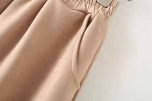 Detail of khaki faux suede trousers showing elastic waistband and side pocket stitching