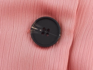 Detail of pink double-breasted suit fabric with marble texture button and pleated texture