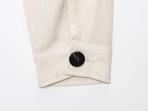 Close-up of cream linen jacket cuff with dark marble button and detailed stitching