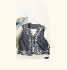Detail of grey vintage denim vest with white floral embroidery and a sleek V-neck