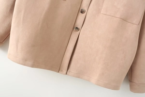 Detail of silver metal buttons and stitching on light coffee suede jacket pockets