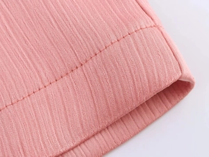 Macro shot of pink fabric texture and fine stitching detail on double-breasted blazer