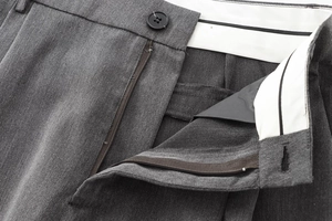 Détail de la taille avec bouton noir et fermeture éclair sur pantalon gris chic
