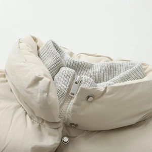 Detail of the stand-up collar and silver zipper on this beige baseball jacket