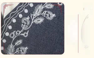Detailed close-up of white floral embroidery on premium dark blue denim vest fabric
