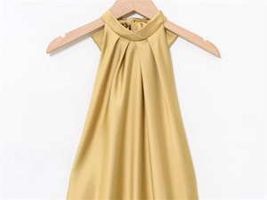 Detail of elegant halter neck pleats and silky satin fabric on the gold party dress