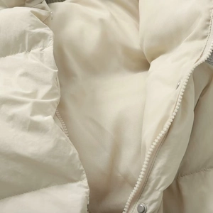 Close-up of beige quilted jacket featuring a high-quality nylon zipper and metal snap buttons