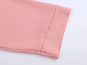 Close-up of pink blazer sleeve with vertical pleated texture and neat stitched edge