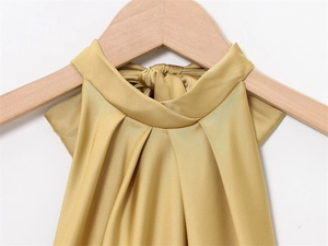 Detail view of champagne gold satin halter dress featuring pleated neckline on wooden hanger