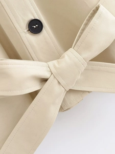 Macro detail of khaki trench coat featuring twill fabric texture and buttoned waist belt