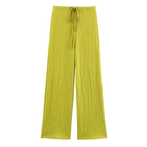 Detail of lime green wide-leg trousers featuring pleated texture and drawstring waist