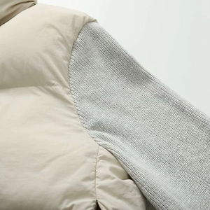 Detail of quilted beige fabric and light grey ribbed knit sleeve texture on jacket