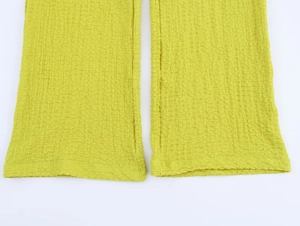 Close-up of grass green crepe fabric texture and hem stitching on casual trousers