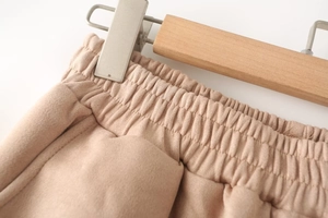 Detailed macro view of beige faux suede trousers featuring elastic high waist and soft texture