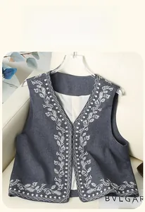 Detailed close-up of gray denim vest featuring delicate white floral embroidery and V-neck