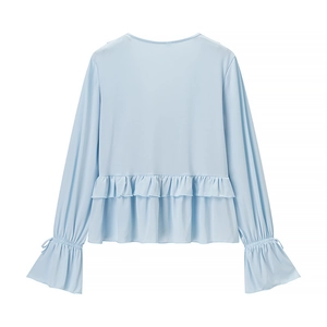Detailed close-up of light blue blouse with layered ruffle waist and elastic cuffs