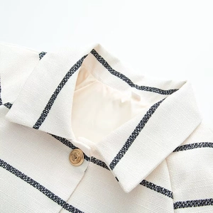 Detailed close-up of textured tweed fabric with navy stripes and a vintage gold button