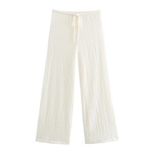 Detailed view of white pleated wide-leg trousers with drawstring elastic waistband