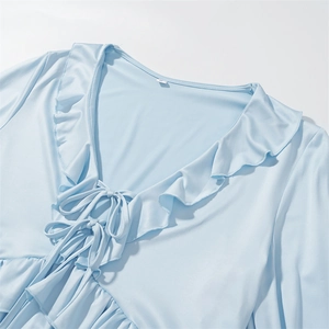 Detail of light blue V-neck top with ruffled trim and tie-up front design