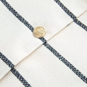 Macro shot of striped tweed fabric texture with a vintage embossed gold crest button
