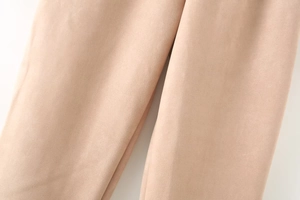 Close-up of soft apricot faux suede fabric showing smooth texture on casual pants