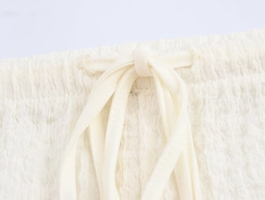 Detail of ivory pleated fabric showing elastic waistband and drawstring cord tie