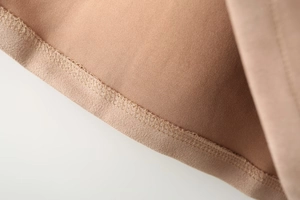 Macro shot of camel faux suede jacket hem featuring precise stitching and texture