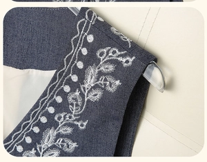 Detailed embroidery of white floral patterns on a vintage blue V-neck denim vest