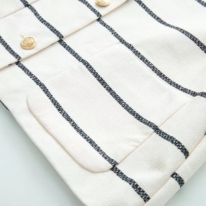 Detailed macro view of the striped tweed fabric texture and gold embossed metal button