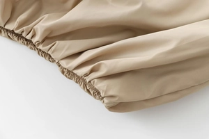 Close-up of khaki jacket's elasticized waist detailing and smooth fabric texture